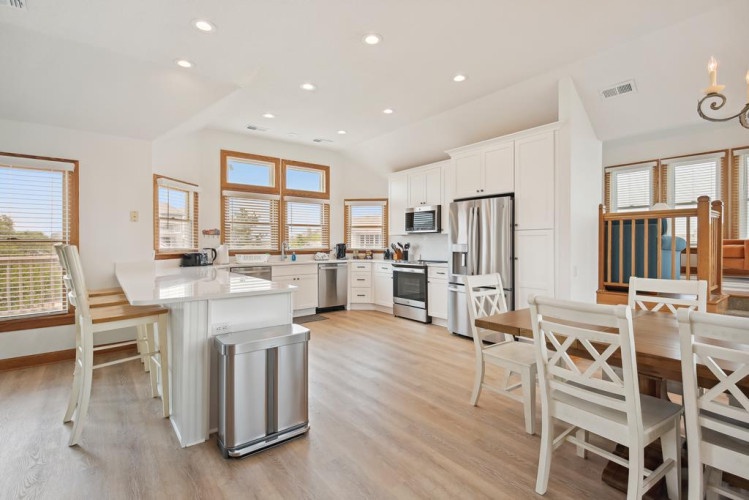 Step into your bright, airy kitchen where natural light pours in through stunning windows. You'll love preparing meals with modern stainless steel appliances and white cabinetry, while your family gathers at the inviting island or dining table.