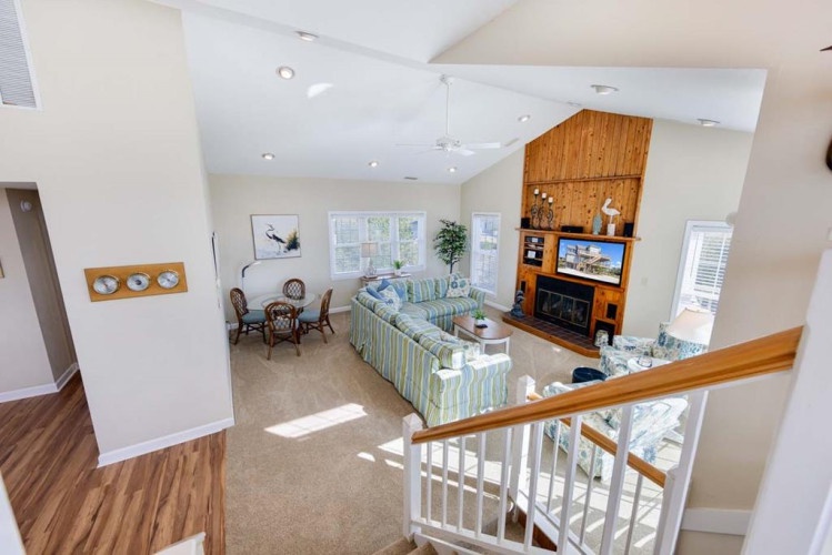 Your bright open-concept living area blends style and comfort—sink into the striped sofa, enjoy coastal charm, and unwind by the warm fireplace after exploring nearby attractions.