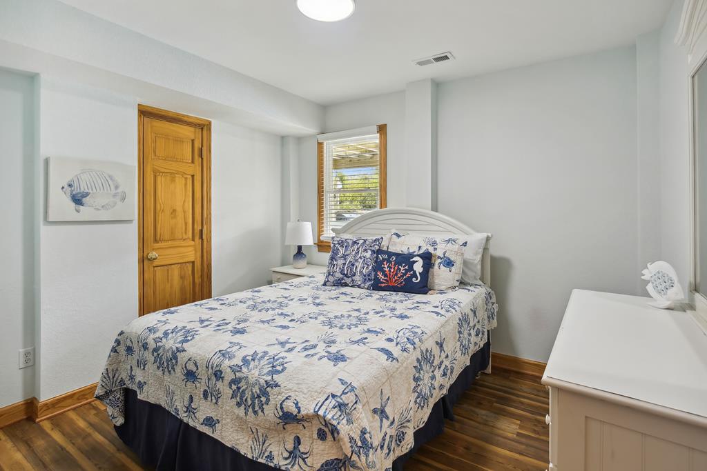 Unwind in your cozy bedroom with coastal charm—blue and white linens, warm wood floors, and a peaceful view to help you settle in and feel right at home.