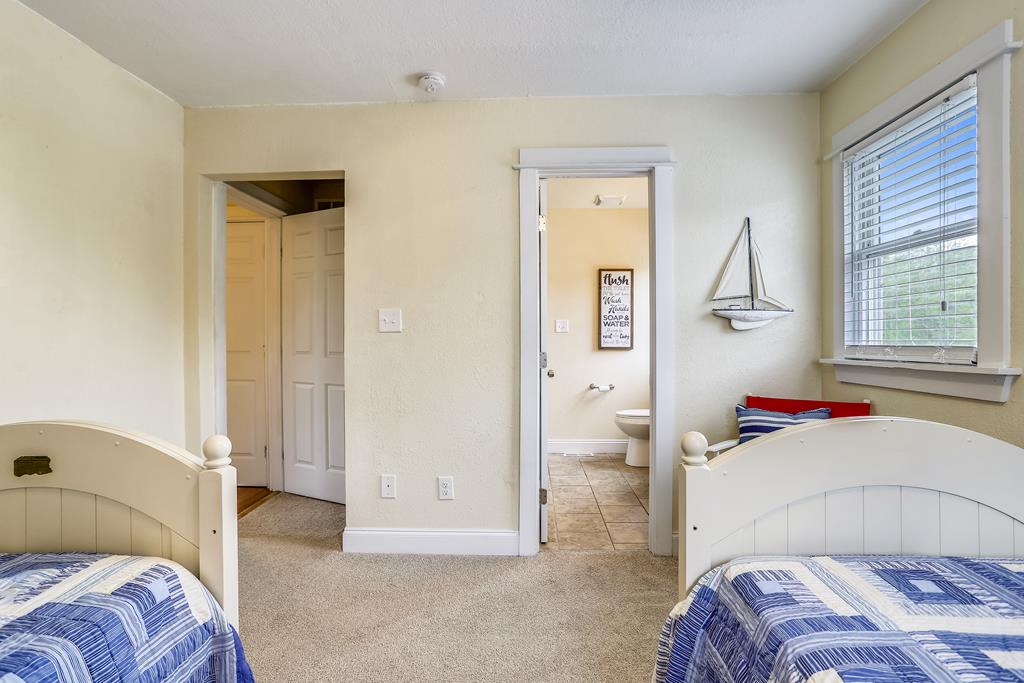 Unwind in this coastal-themed bedroom with twin beds dressed in nautical stripes, soft natural light, and your own ensuite bathroom just steps away.