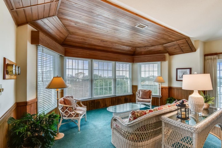 Relax in this sun-filled lounge with vaulted wood ceilings, wicker seating, and expansive windows framing serene outdoor views—your perfect retreat after a day exploring.