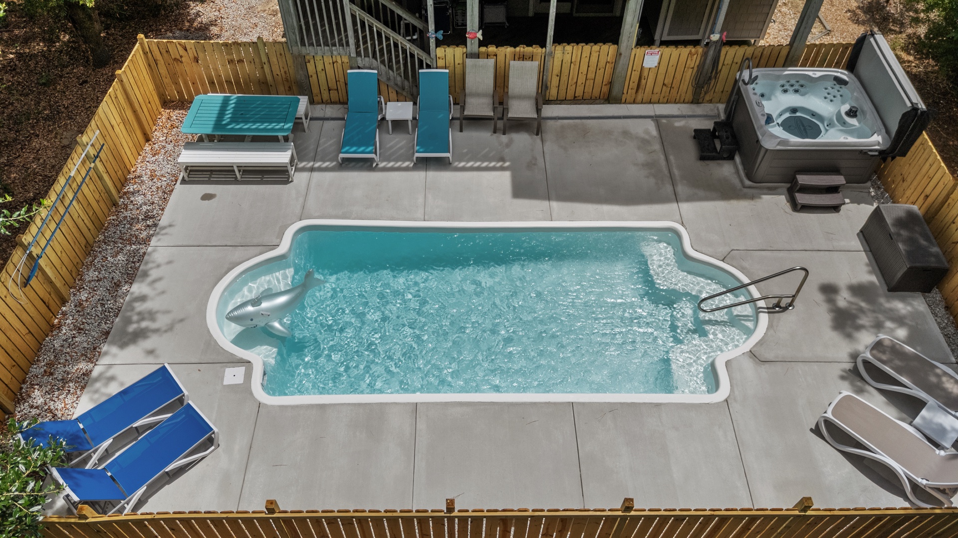Aerial view of the private outdoor pool and hot tub area, surrounded by loungers and enclosed by wooden fencing for privacy.
