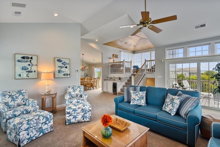 Sink into plush seating under soaring vaulted ceilings and let the ocean breeze drift in through oversized windows. Your coastal retreat awaits, blending comfort with breezy elegance.
