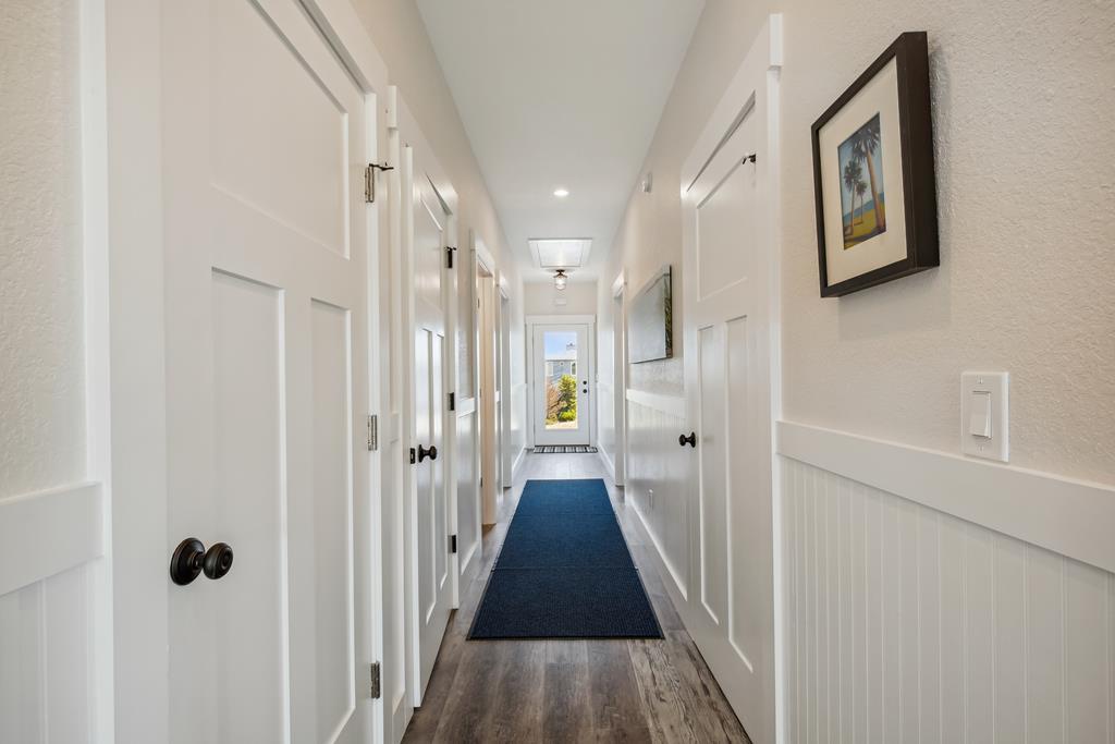 A bright hallway connects private spaces, where fresh coastal artwork and vintage-style details set a calm, welcoming tone—natural light streams from the far end, inviting you into your coastal retreat.