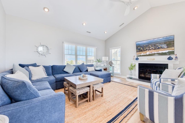 Settle into your bright, airy living room featuring vaulted ceilings, plush navy sofas, and a cozy fireplace—perfect for unwinding after a day of adventures.