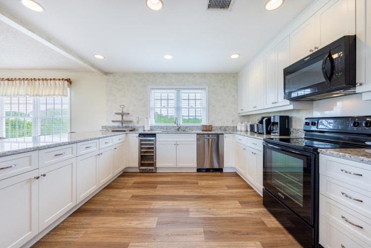 You'll love preparing meals in this bright, spacious kitchen with sleek white cabinetry, granite counters, stainless steel appliances, and beautiful hardwood floors that invite you to cook and gather comfortably.