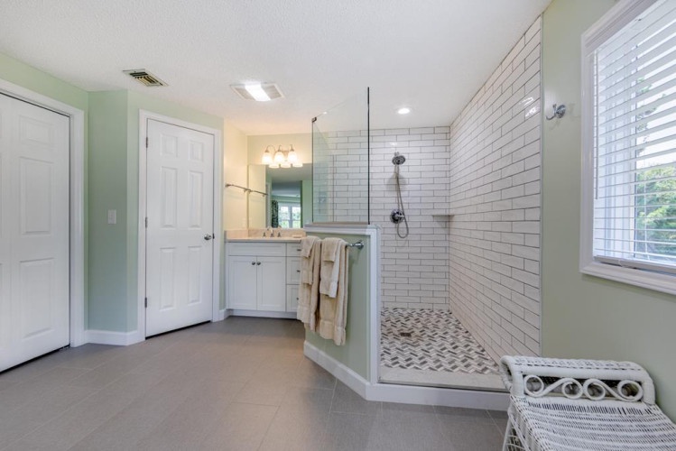 Step into your spacious private bathroom, where white subway tiles and soft mint walls create a fresh, calming retreat. Your walk-in shower awaits after a day exploring the area.