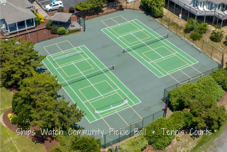 Ships Watch Community features well-maintained tennis and pickleball courts surrounded by coastal trees and nearby vacation homes in a peaceful residential setting.