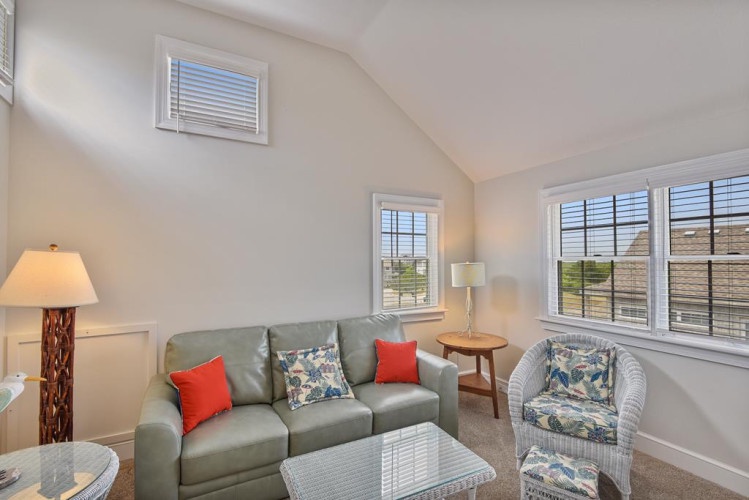 Relax in your bright, airy living space with vaulted ceilings and coastal-inspired decor, where natural light pours through multiple windows, inviting you to unwind in comfort after a day of adventure.