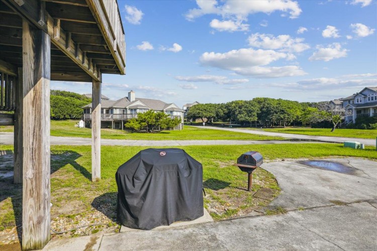 The property overlooks a spacious green common area with neighboring homes, offering a peaceful coastal community setting ideal for relaxation and outdoor activities.