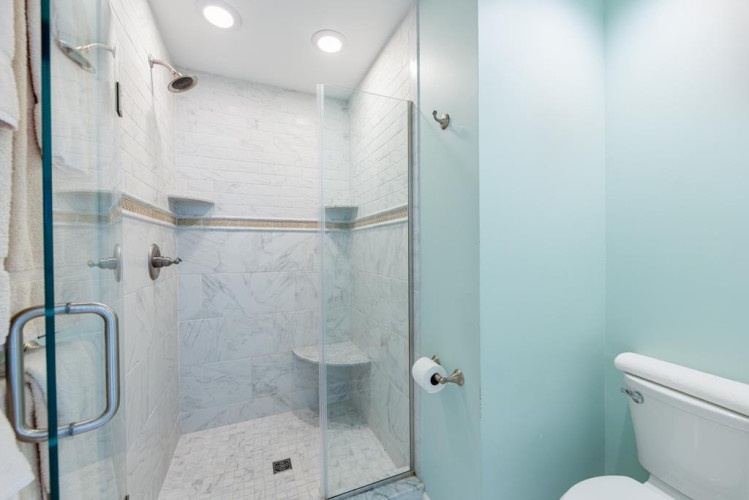Your private bathroom features a spacious walk-in shower with elegant marble-look tile and a built-in corner seat for ultimate relaxation.