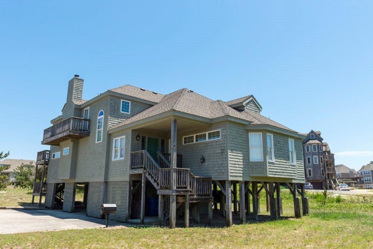 A spacious coastal home elevated on stilts, offering proximity to the beach and ocean breezes with ample outdoor space surrounding the property.
