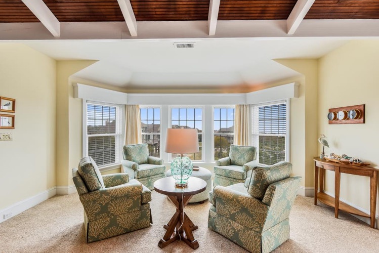 Relax in your bright, airy living space with vaulted wood-beam ceilings and a sunlit bay window seating area overlooking peaceful views. Sink into comfortable chairs and let natural light fill the room.