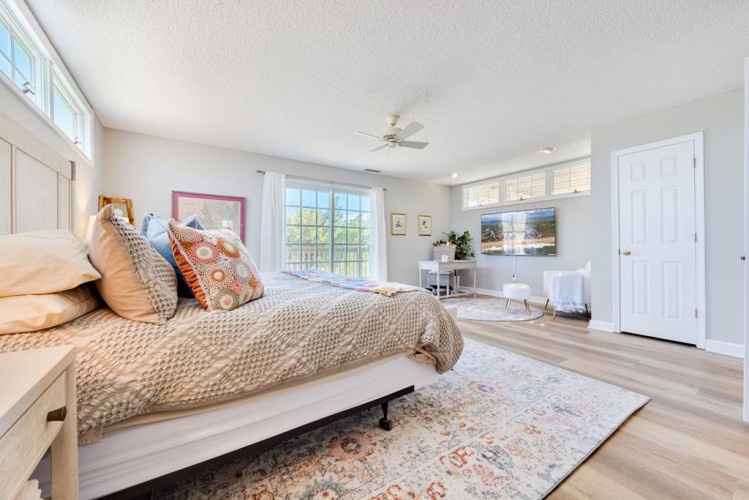 Drift off in your sun-filled bedroom with a plush bed, cozy linens, and peaceful views through large windows that invite natural light to flow in.