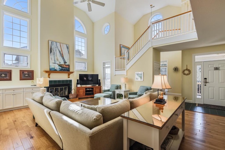 Your spacious living room features soaring two-story ceilings with abundant natural light, a cozy fireplace, and elegant wood floors that flow through this sun-filled gathering space.
