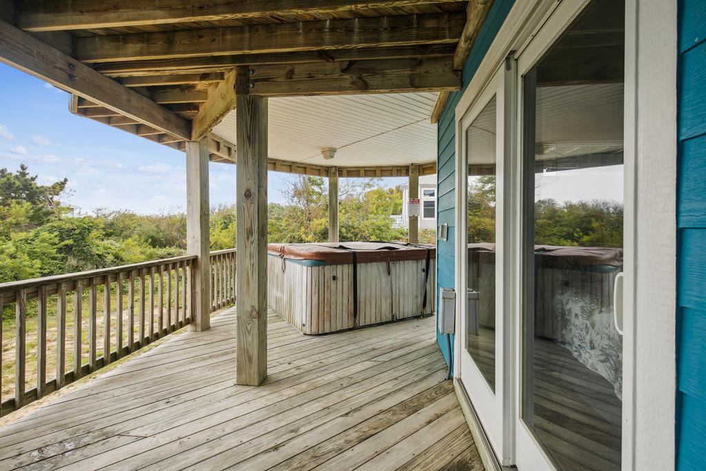 Your private covered deck features a soothing hot tub surrounded by lush greenery, perfect for unwinding under the open sky while staying sheltered overhead.