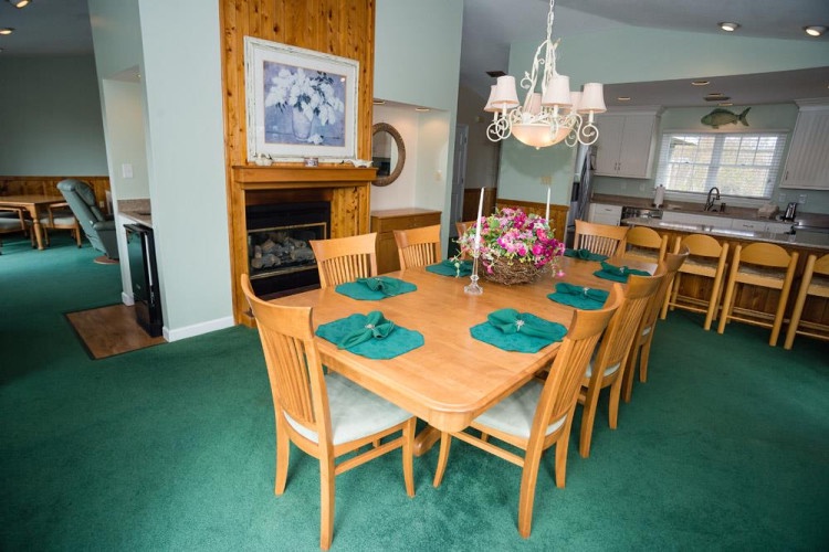 Gather around this spacious dining table where your group can share meals and stories. The cozy fireplace and open layout connect you to the kitchen, making every moment together feel effortless and warm.