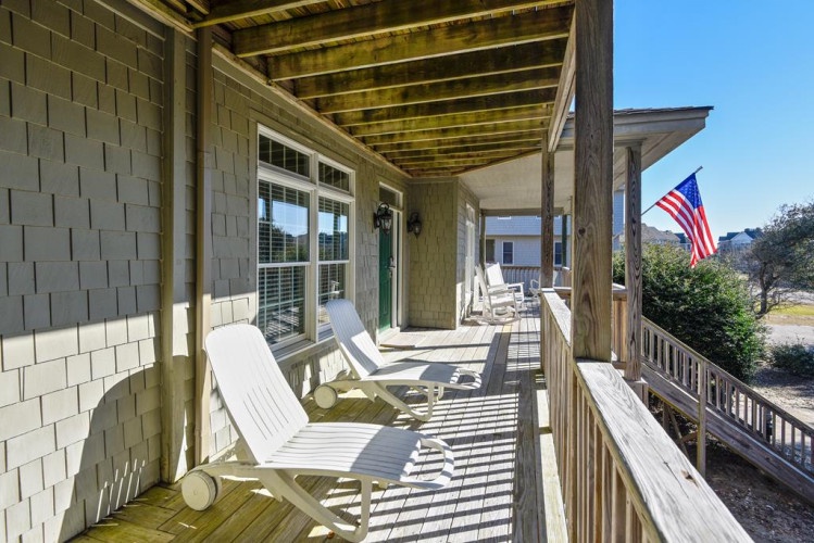 Step onto your private front porch and settle into a comfortable lounge chair where you can unwind beneath the covered veranda. An American flag waves nearby as gentle breezes and dappled sunlight create the perfect spot to start your mornings.