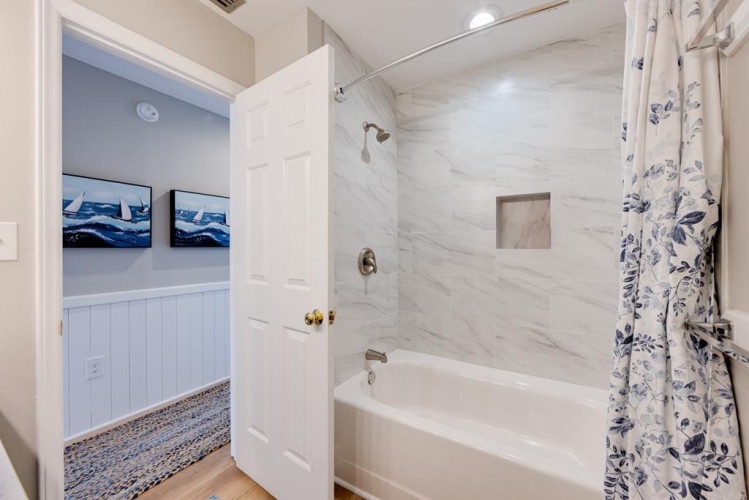 Fresh white marble-style tiles and a rainfall shower transform your private bath into a serene escape after a long day of coastal adventures.