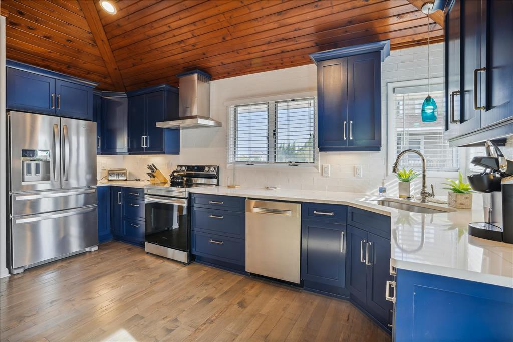 Your fully equipped kitchen features rich navy cabinetry, gleaming stainless appliances, and warm wood ceilings—a bright, stylish space where you can whip up your favorite meals in comfort.