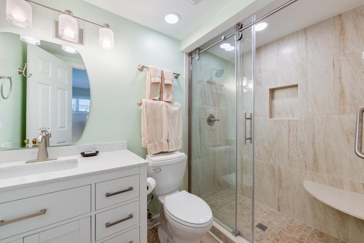 Refresh in your private spa-like bathroom, complete with a sleek glass-enclosed shower, modern vanity, and soothing mint-green walls that set a peaceful tone.