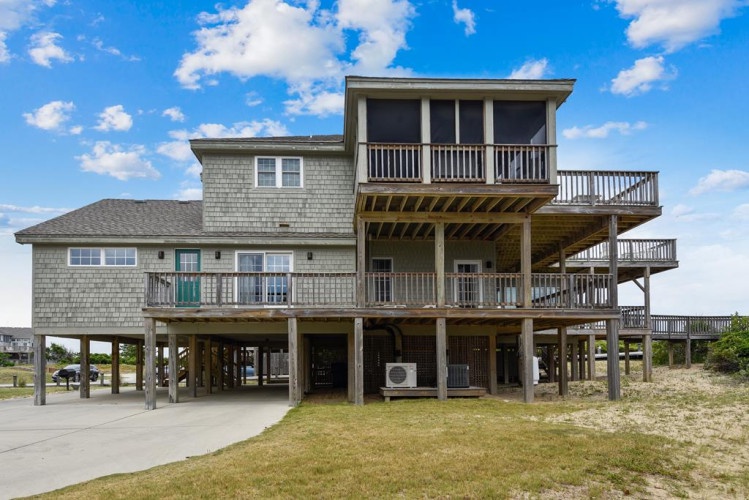 The property stands elevated on stilts with expansive multi-level decks, offering a classic coastal design built to embrace ocean breezes and scenic views in a quiet beach area.