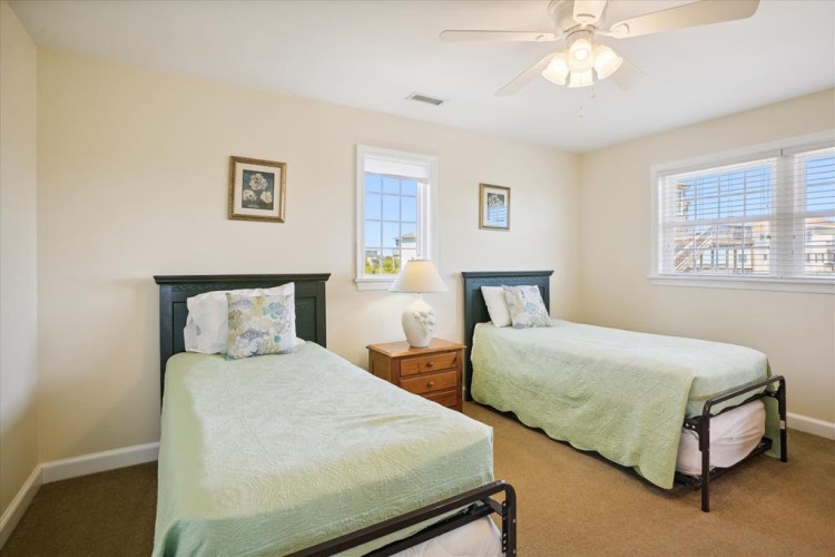 Your comfortable twin bedroom awaits with fresh linens, soft natural light from double windows, and a ceiling fan to keep you cool during warm summer nights.