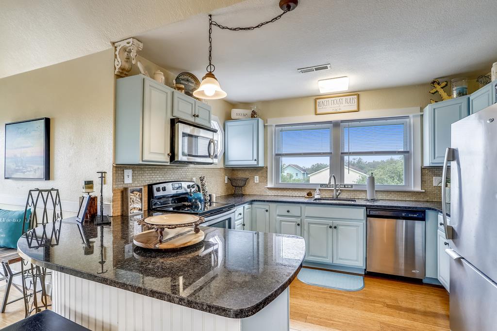 Your fully equipped kitchen features granite counters, stainless appliances, and charming coastal touches—ready for morning coffee or preparing a homemade meal with a view.