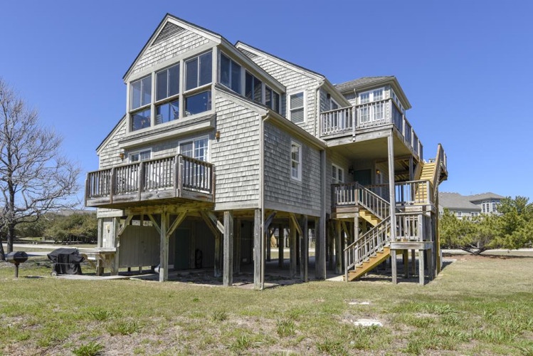 Classic coastal architecture elevated on stilts, offering multi-level deck access and spacious outdoor grounds near waterfront areas.