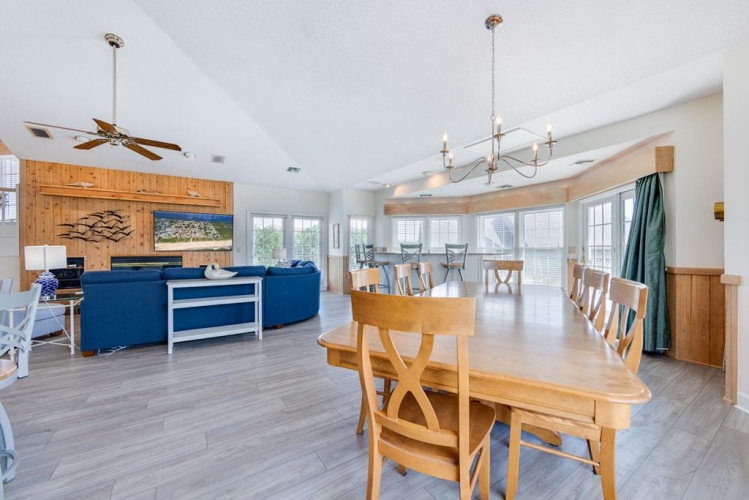 Step into this inviting open-concept space where living, dining, and kitchen areas blend seamlessly. Natural light floods through large windows, highlighting warm wood accents and vaulted ceilings perfect for your relaxing getaway.