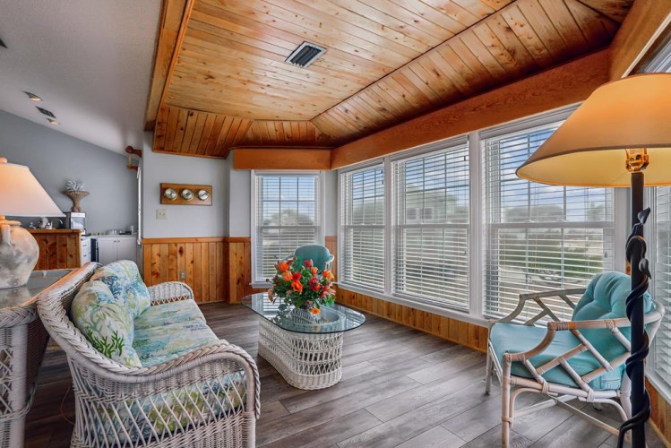 Unwind in your private sunroom where vaulted wood ceilings and expansive windows frame peaceful vistas, inviting natural light into every corner of this cozy retreat.
