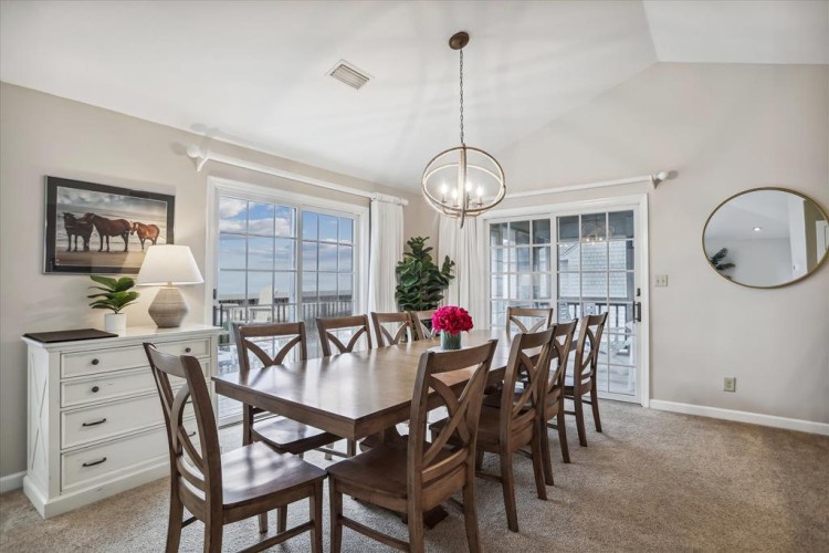 Gather around this spacious dining table where your group can share meals and stories together. Natural light pours through large windows, and glass doors open to your private balcony beyond.