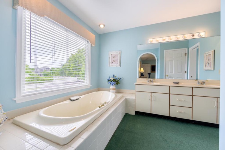 Sink into serenity in your spacious private bathroom, where a luxurious soaking tub beneath bright windows invites you to unwind after exploring nearby attractions.