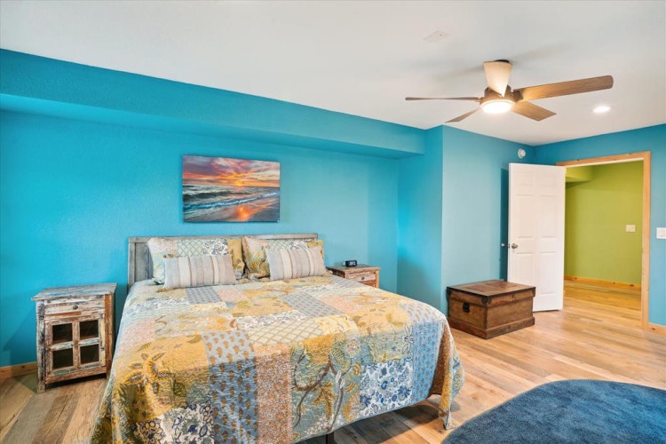 Wake up to vibrant turquoise walls and coastal charm, where your peaceful retreat meets beachy comfort. The soft ceiling fan and cozy bedding invite you to unwind completely.