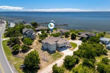 Waterfront property nestled along a serene bay, surrounded by lush greenery and offering direct beach access with a private dock extending into calm waters.