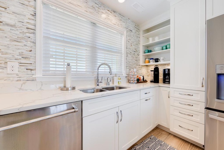 A bright, modern kitchen awaits you with stylish marble countertops, stainless steel appliances, and coffee-making essentials ready for your morning routine.