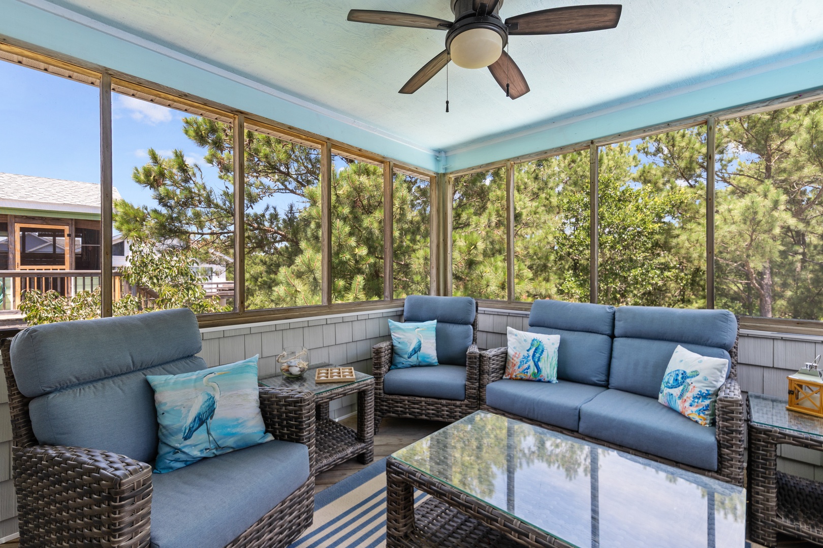 Your enclosed sunroom offers plush seating, peaceful tree views, and gentle breezes—perfect for sipping morning coffee or unwinding after the beach.