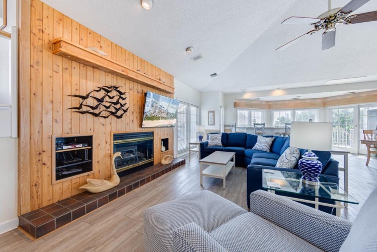 Sink into comfort in your spacious living room, where a cozy fireplace, ceiling fan, and plush seating invite you to unwind after beach adventures.