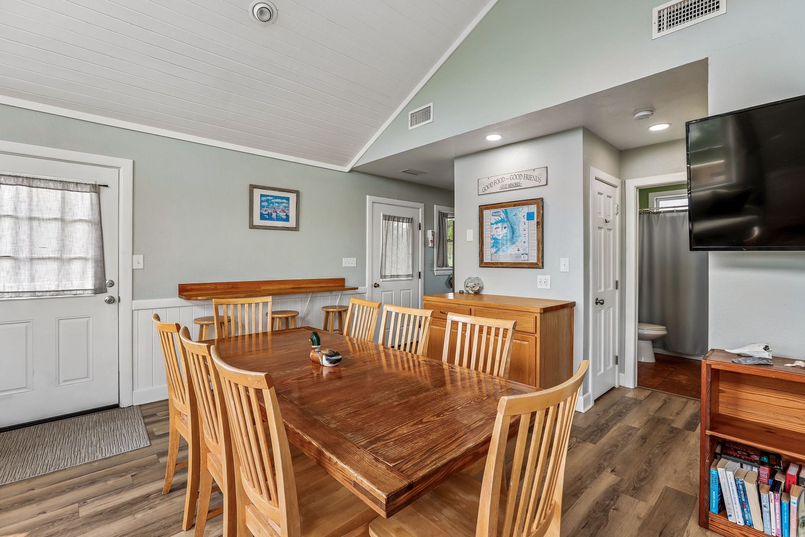 Gather around your spacious dining table under vaulted ceilings, with coastal charm in every corner. This light-filled space flows effortlessly from kitchen to living area, perfect for morning coffee or evening meals together.