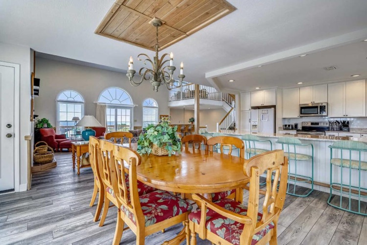 Step into your coastal-inspired living space where soaring ceilings and arched windows flood the open-plan layout with natural light, connecting dining, living, and kitchen areas for effortless entertaining and relaxation.