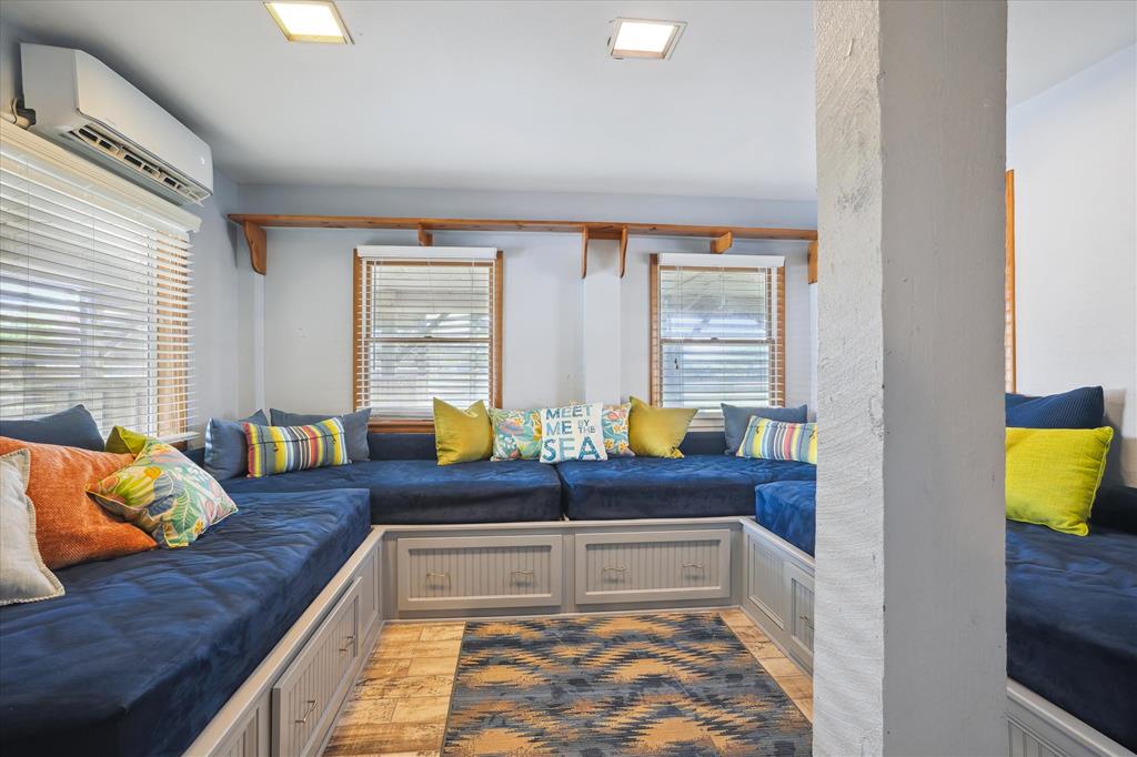 Sink into plush blue seating surrounded by cheerful pillows and warm wood accents. Your bright, airy retreat awaits with modern comfort and playful coastal touches.