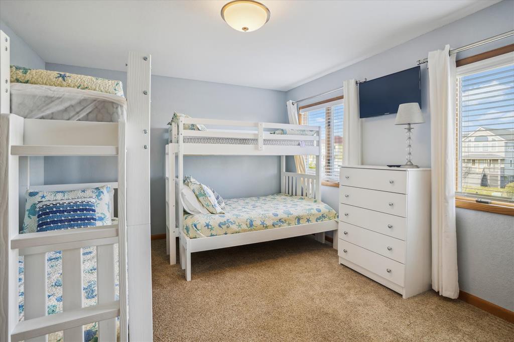 Your family's cozy retreat awaits with cheerful bunk beds perfect for kids, all brightened by natural light streaming through generous windows. Fresh coastal hues and soft carpeting create a welcoming space where memories are made.