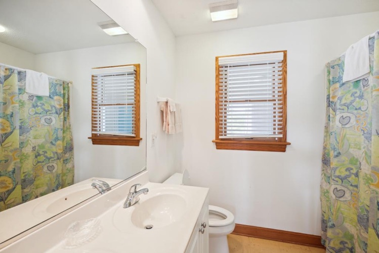 A bright, clean bathroom with double sinks gives you plenty of room to freshen up. Natural light pours in through wooden blinds, creating a cheerful, relaxed space to start your day.