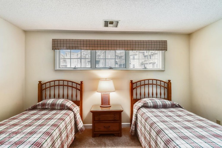 Two comfortable twin beds await, each dressed with coordinating plaid linens, offering restful sleep for you and your travel companion in this cozy retreat.