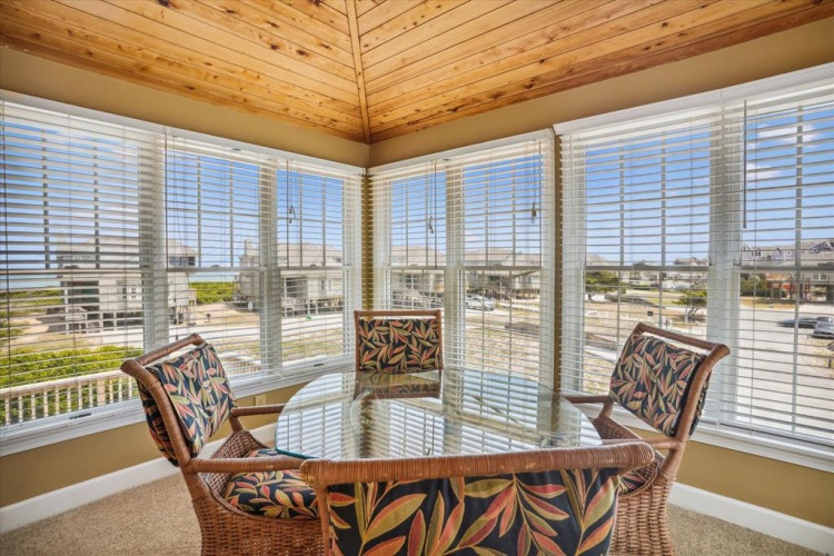 Settle into your private sunroom surrounded by floor-to-ceiling windows that invite natural light and stunning views. The warm wood ceiling and tropical-print seating create a peaceful retreat for your morning coffee.
