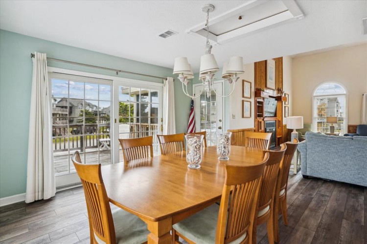 Step into this inviting dining space where natural light pours through expansive doors, perfect for enjoying meals with loved ones around the elegant wood table.