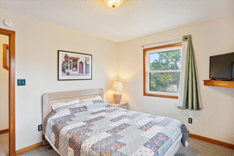 Your bright, peaceful bedroom features a cozy queen bed, natural daylight, and woodland views from your window—perfect for restful mornings.