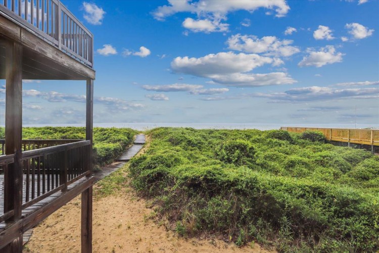 Beachside property with direct boardwalk access through lush coastal dunes to the ocean, offering a serene natural setting and convenient beach access.
