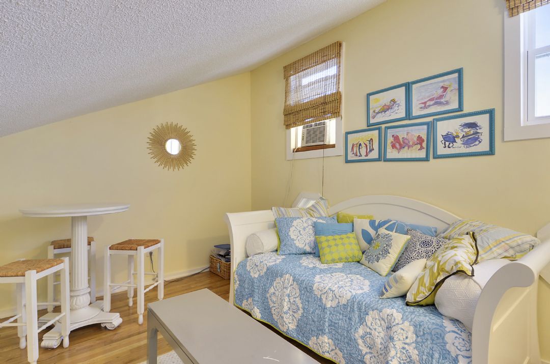 Curl up in this cozy bedroom where cheerful yellow walls and playful artwork set a lighthearted tone. The daybed invites you to relax with a good book or drift off to sleep surrounded by soft pillows and coastal-inspired decor.