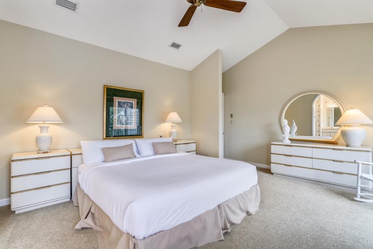 Sink into plush bedding beneath vaulted ceilings, where gentle lamps and a ceiling fan create your perfect sleep haven. Ample dresser space keeps everything organized.